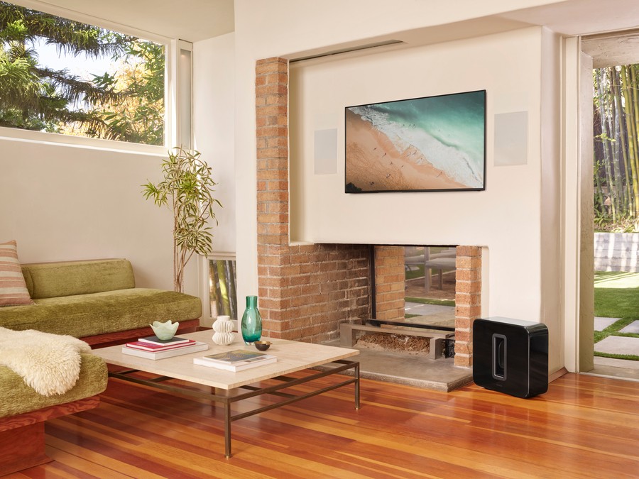 a living room with a TV installed over the fireplace in front of sofas and a coffee table