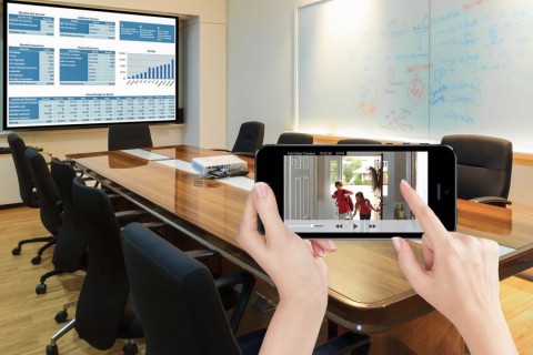 A conference room with an overlayed image of hands holding a smartphone displaying a picture of kids arriving home.