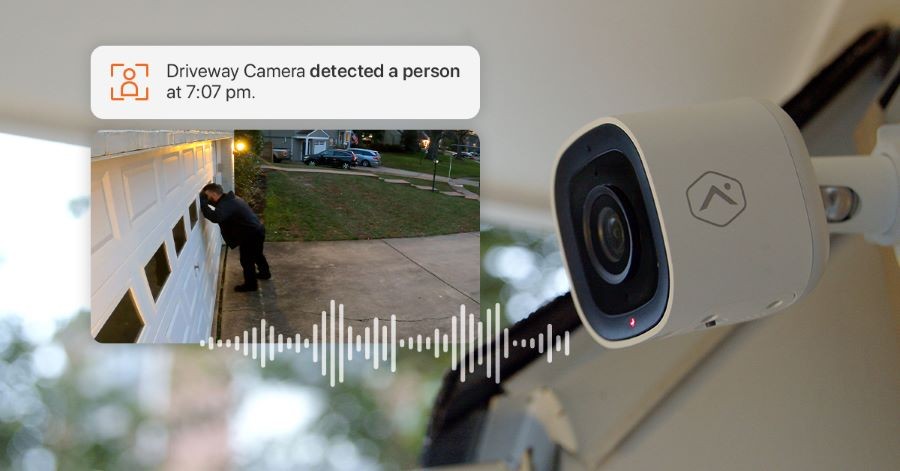 An Alarm.com security camera capturing a man peering into a garage with a timestamp and video clip. 