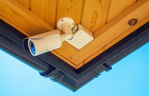 A security camera under a building’s eaves.