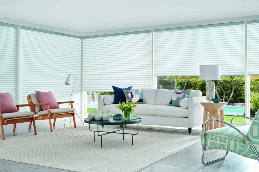 Modern living area overlooking a pool with shades lowered to lessen light and heat.